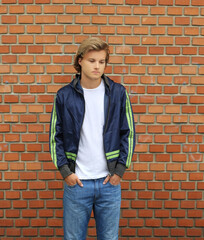 Handsome young man standing against brick wall background