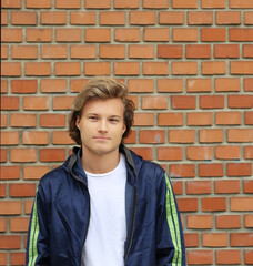 Handsome young man standing against brick wall background