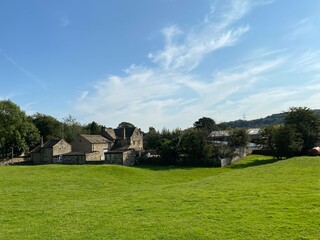 Fototapeta na wymiar Rural view of Esholt village, with a large meadow, houses and a farm, on a sunny day near, Bradford, Yorkshire, UK