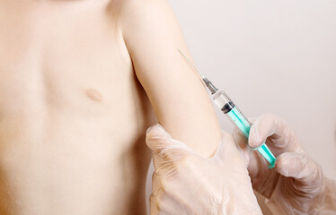 The doctor vaccinates the child in the shoulder. The concept of routine vaccination of the...