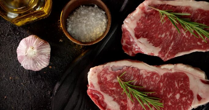 Steak striploin raw with rosemary and spices on the table. 
