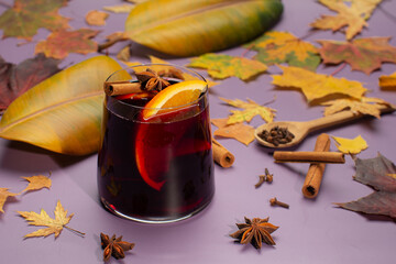 Mulled wine with cinnamon,oranges,anise stars and autumnal,yellow leaves on purple...
