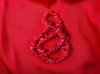 Red coral beads on a red background. International Women's Day.