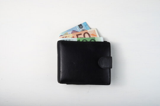 Black Wallet With Euro Sticking Out On White Background