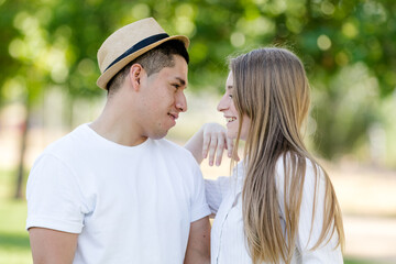 young couple looking into each other's eyes in a park. Latin man and Caucasian woman