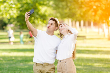 Young couple taking a selfie on their mobile in the park. Latin man and Caucasian woman