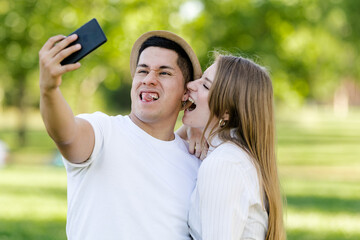 Young couple taking a selfie on their mobile in the park. Latin man and Caucasian woman