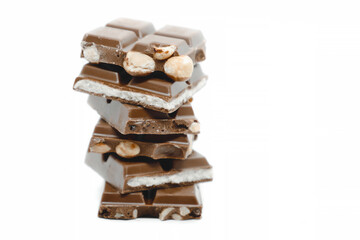 The chocolate pieces of different types stacked on white background.