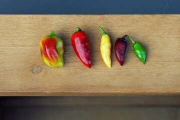 View of five different homegrown chilies on a wood