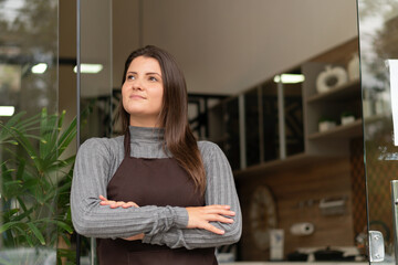 Happy brazilian female entrepreneur with crossed arms looking up in front of store facade. owner, small business, successful, community concept..