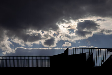 clouds with sunbeams and a silhouette of a building