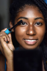 Young black woman applying make up