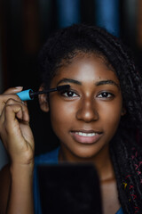 Young black woman applying make up