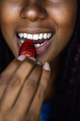 Young black woman eating a strawberry