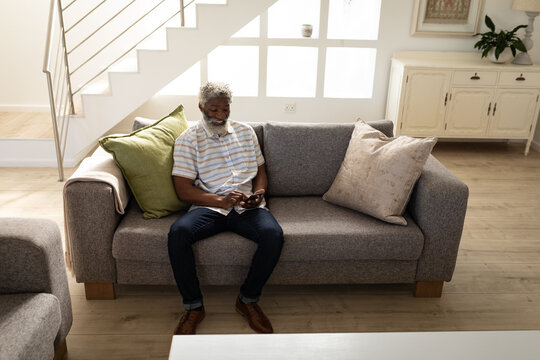 Black African American Senior man using smartphone while sitting on the couch at home