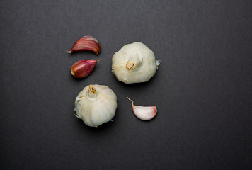 Bodegón de cabezas de ajos con dientes de ajo sobre fondo liso de color oscuro