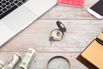 Laptops and mobile phones, dollar bills and other related items surround a pocket watch