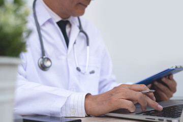 Doctor working on laptop computer and review report in medical office