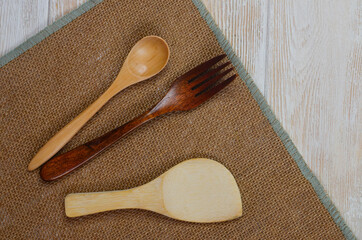 Wooden kitchen appliances spoon fork on a wooden kitchen table with space for text, eco tableware...