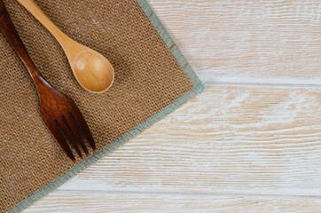 Wooden kitchen appliances spoon fork on a wooden kitchen table with space for text, eco tableware...
