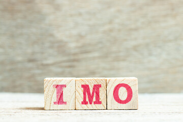 Alphabet letter block in word IMO (Abbreviation of in my opinion) on wood background