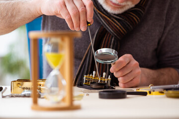 Old male watchmaker working in the workshop
