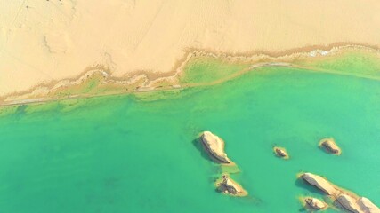 aerial view of desert and green lake 