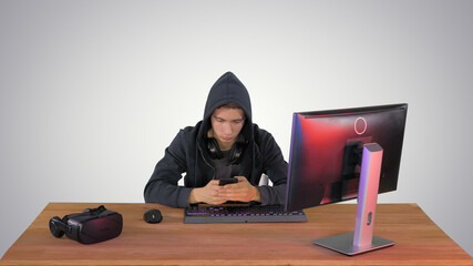 Hooded hacker using laptop and smartphone on gradient background