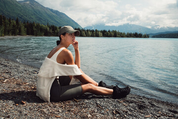 Young woman sit and relax on the mountain lake wearing sport clothes in Alaska trip