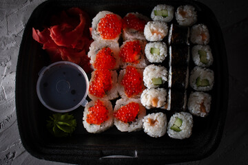 Various kinds of sushi in black food box, flat lay food
