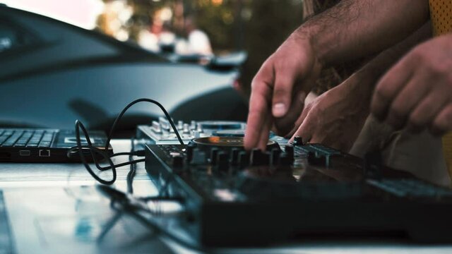 DJ mixes music tracks on a remote control outdoors