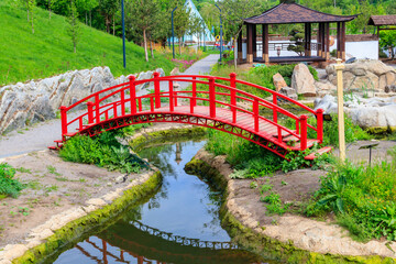 Red bridge and gazebo by a pond in Japanese garden
