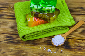 Set of handmade soap bars, sea salt and towel on wooden background. SPA concept