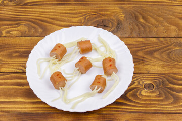 Spaghetti with sausages in the shape of spiders for Halloween party on wooden table