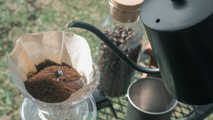 Hand drip coffee in the camp, A man pouring water on coffee ground with filter.Drip coffee and camping.