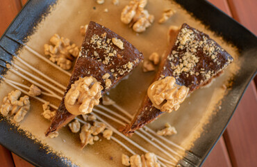 Two pieces of pecan pie on an elegant plate. Dessert decorated with walnuts.