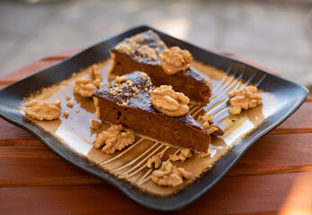 Two pieces of pecan pie on an elegant plate. Dessert decorated with walnuts.
