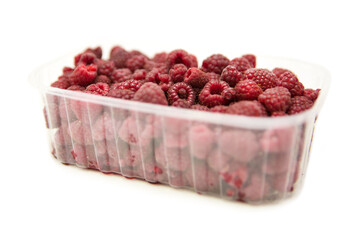 Fresh ripe organic raspberries berries in plastic container isolated on white background