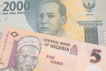 A macro image of a grey two thousand Indonesian rupiah bank note paired up with a orange, plastic five naira note from Nigeria.  Shot close up in macro.