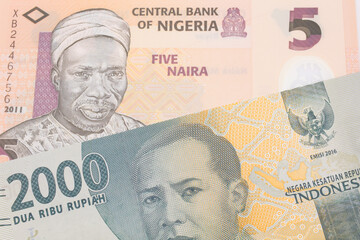 A macro image of a grey two thousand Indonesian rupiah bank note paired up with a orange, plastic five naira note from Nigeria.  Shot close up in macro.