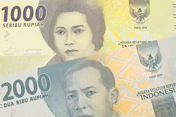 A macro image of a grey two thousand Indonesian rupiah bank note paired up with a green one thousand bank note from Indonesia.  Shot close up in macro.