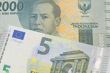 A macro image of a grey two thousand Indonesian rupiah bank note paired up with a blue, green and white five Euro note.  Shot close up in macro.