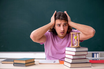 Young male student in the classroom at time management concept