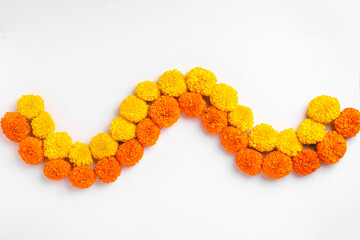 Flower Rangoli for Diwali Festival made using Marigold and leaf and Oil Lamp over white background,