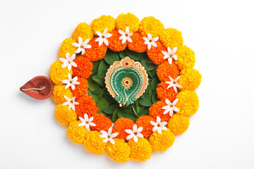 Flower Rangoli for Diwali Festival made using Marigold and leaf and Oil Lamp over white background,