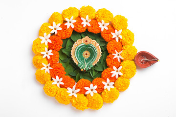 Flower Rangoli for Diwali Festival made using Marigold and leaf and Oil Lamp over white background,