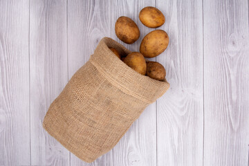 New potato isolated in a jute bag on wooden background