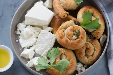 Greek baked mini spiral pies made of phyllo dough, spinach and feta cheese on a grey plate, elevated view, close-up