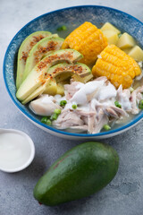 Plate of colombian ajiaco or potato, chicken and corn stew topped with avocado slices and sour cream, selective focus, vertical shot