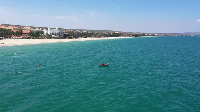 Drone flies around the fishing boat. the boat sails in the beautiful turquoise sea, the kiter rides alongside. Aerial view to ship  in beautiful blue ocean